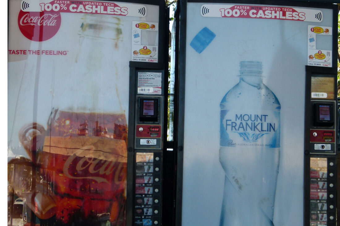 Photo of two soft drink vending machines. Both say "100% cashless" at the top.