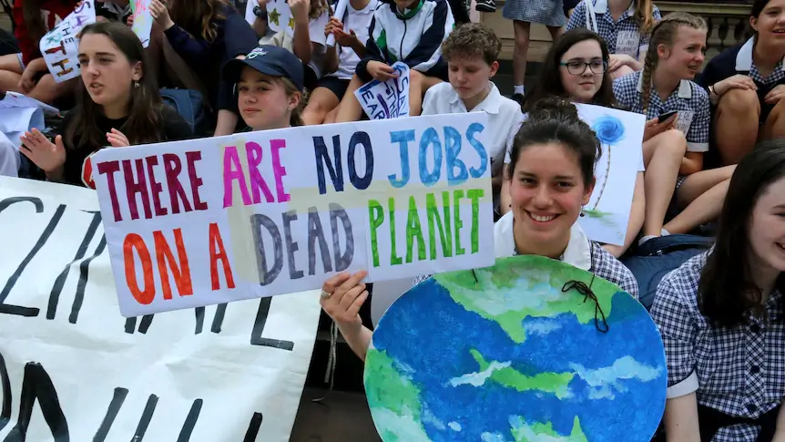 Protester with an Earth costume holding a sign that says, "There are no jobs on a dead planet."