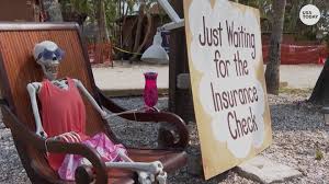 Skeleton sits in lounge chair with a cocktail, next to a sign that says, "Just waiting for the insurance check."